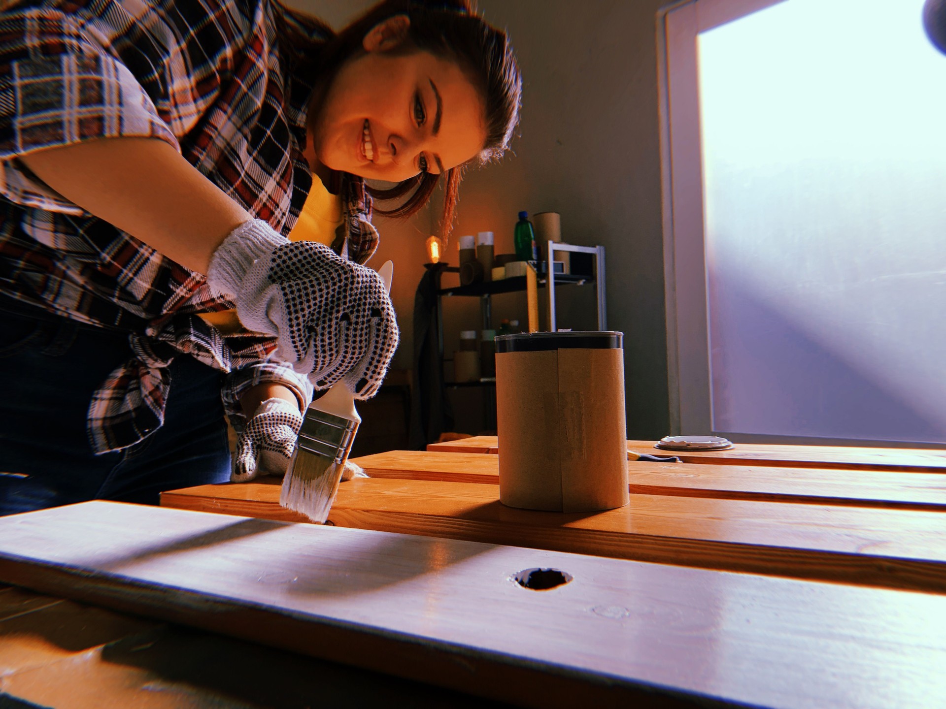 Woman painting plank in garage