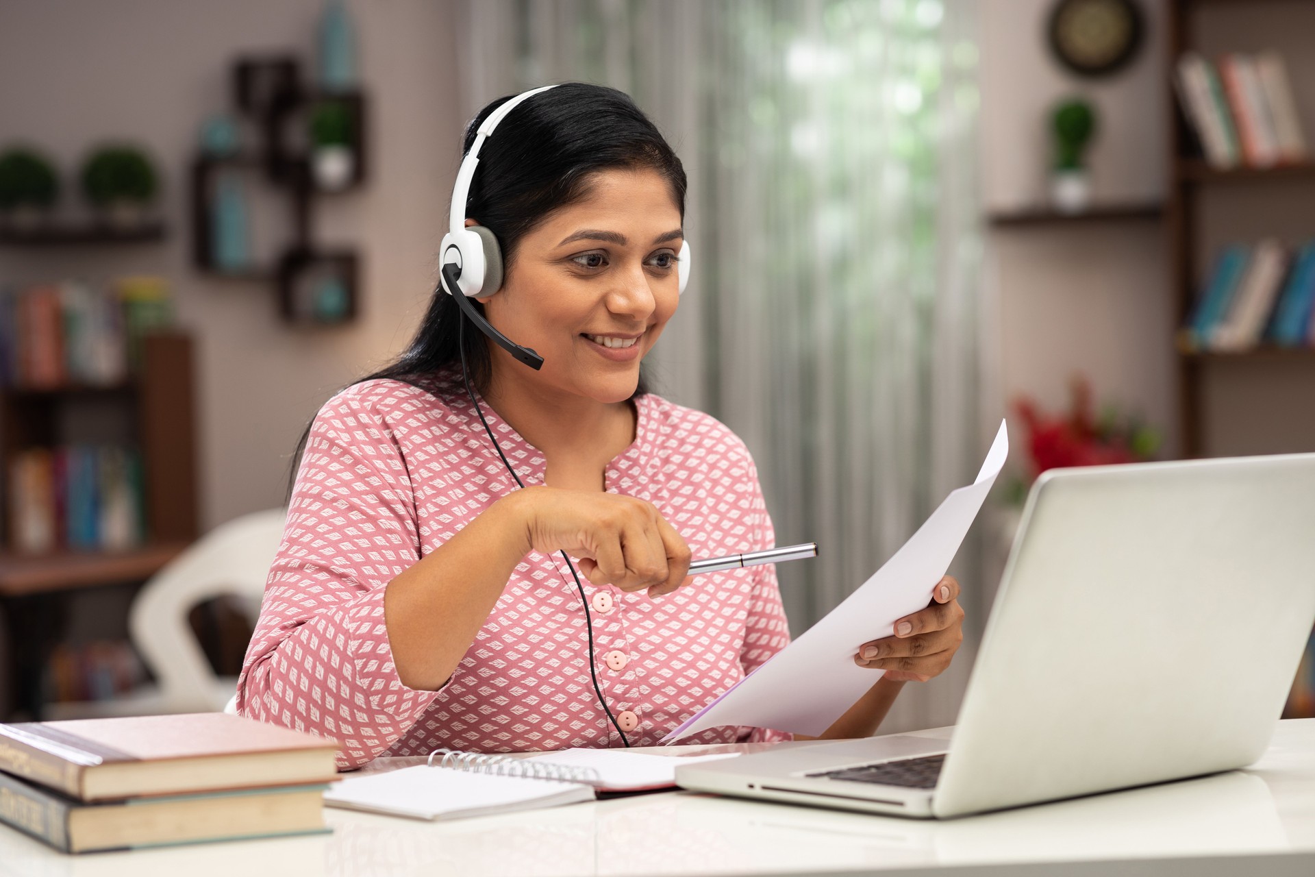Happy business women and teacher with headphones using laptop for video call:- stock photo